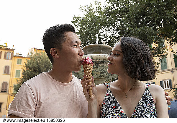 Attractive mixed race couple enjoying gelato in front of fountain