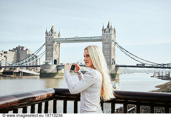 Attractive thoughtful woman taking picture of Tower Bridge