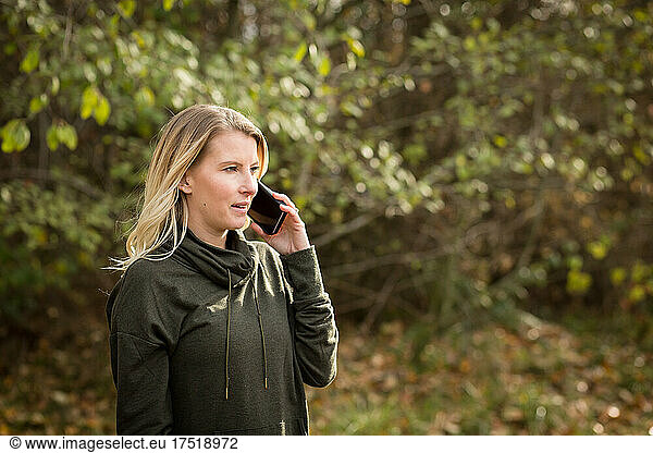 Attractive woman in sweatshirt talks on phone outdoors