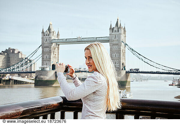 Attractive woman taking picture of Tower Bridge