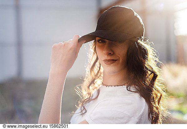 Attractractive millennial woman with long curly hat wearing a cap