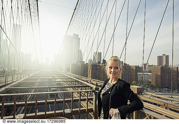 Attraktive Frau steht auf einer Brücke in einer städtischen Metropole