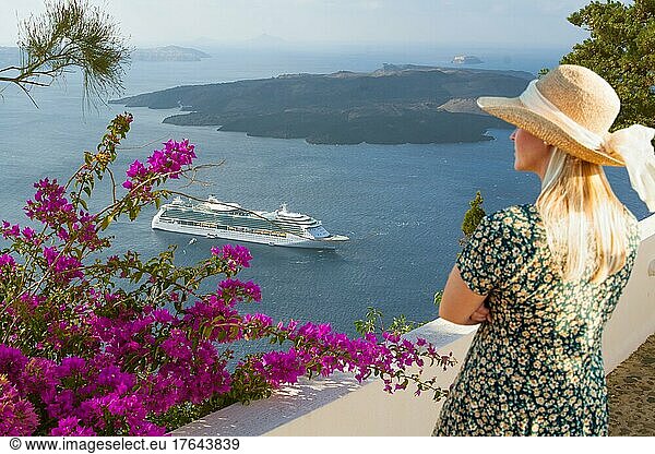 Attraktive weibliche Touristin bewundert die Aussicht auf das Kreuzfahrtschiff vor der Küste von Santorini Griechenland