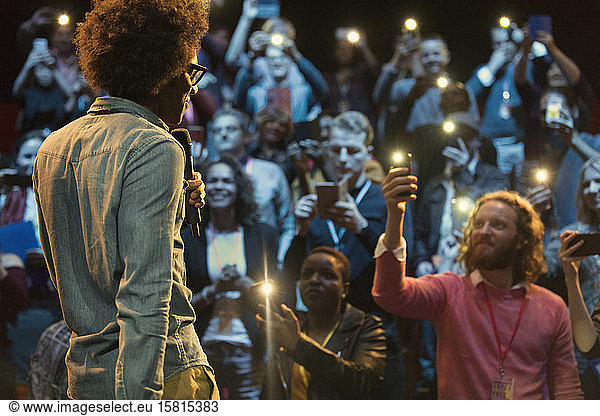Audience using smart phone flashlights  watching speaker