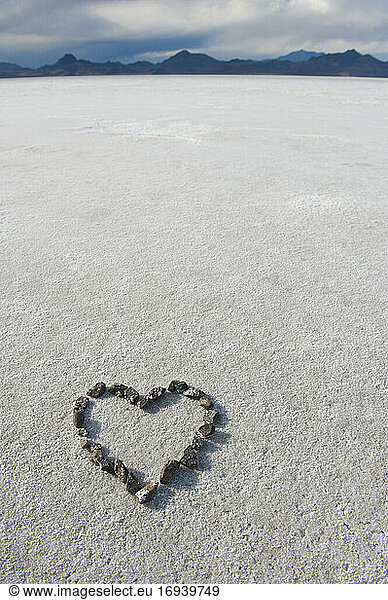 Auf der Salzfläche angeordnete Kieselsteine in Form eines Herzens.