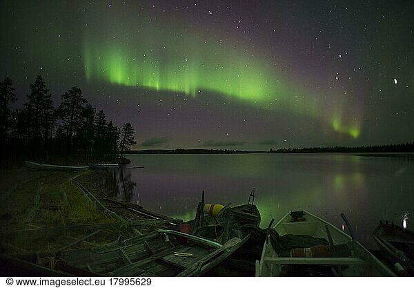 Aurora and stars over the lake with stranded canoes at night  Muonio  Lapland  Finland  Europe