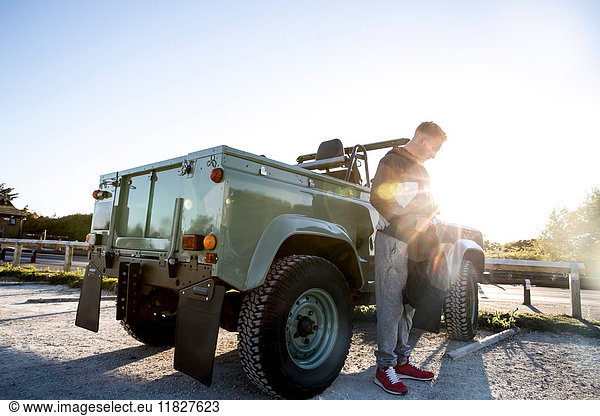 Ausbildung eines jungen Mannes,  Vorbereitung eines Rucksacks mit Cabrio-Allradantrieb auf dem Küstenparkplatz