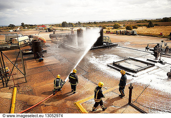 Ausbildung von Feuerwehrleuten  Feuerwehrmänner sprühen Feuerlöschschaum am Öllagertank der Ausbildungseinrichtung