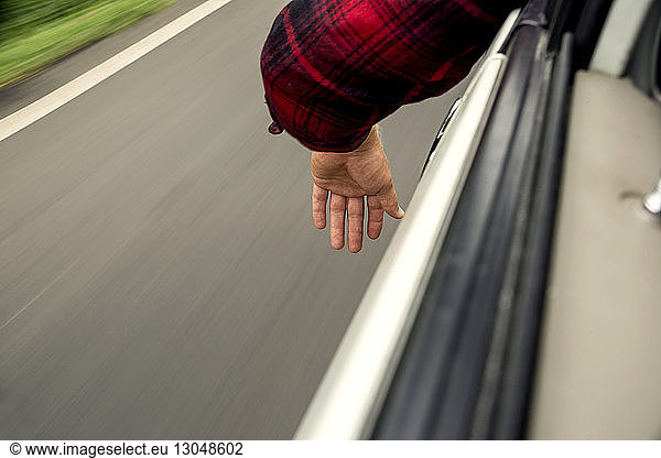 Ausgeschnittenes Bild einer Hand durch ein Autofenster gesehen