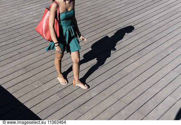Ausschnitt einer Frau im Sonnenkleid mit Handtasche