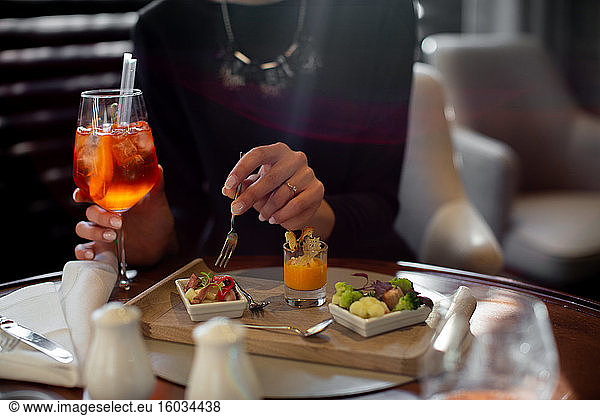 Ausschnitt einer jungen Frau  die in einem Boutique-Hotel wohnt und einen Aperitif isst