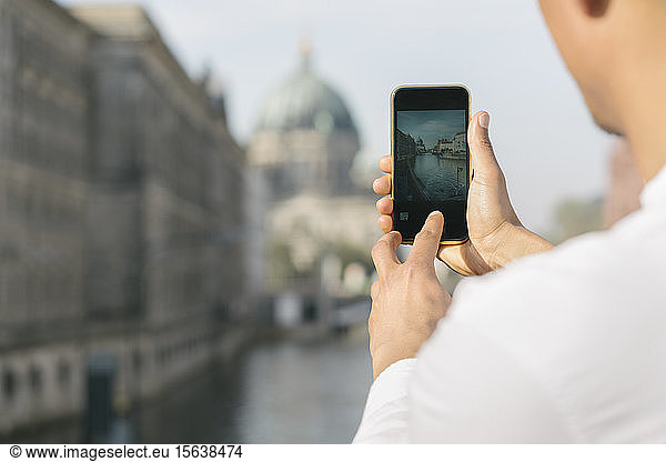Ausschnitt eines Mannes  der mit einem Smartphone ein Foto vom Stadtzentrum aufnimmt  Berlin  Deutschland