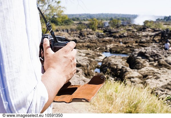 Ausschnitt eines Mannes mit Kamera bei Victoria Falls  Sambia