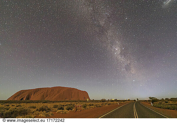 Australia  Northern Territory  Milky Way galaxy over Uluru (Ayers Rock) and empty highway at dusk