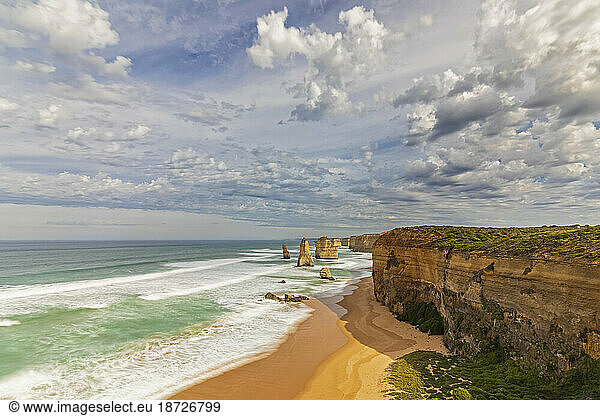 Australia  Victoria  View of clouds over sandy beach in Port Campbell National Park with Twelve Apostles in background