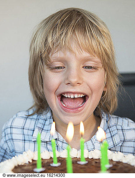 Austria,  Boy laughing and looking at birthday cake,  close up