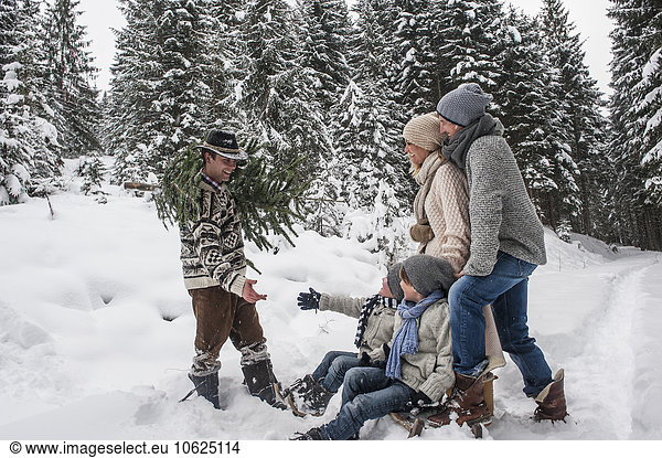 Austria  Altenmarkt-Zauchensee  man with Christmas tree and family together in winter forest
