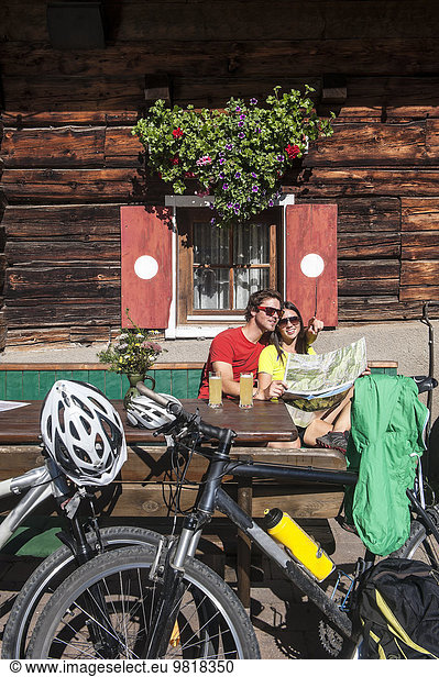 Austria  Altenmarkt-Zauchensee  young couple with mountain bikes at alpine hut