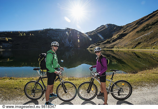 Austria  Altenmarkt-Zauchensee  young couple with mountain bikes at mountain lake