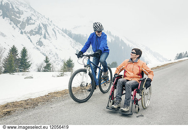 Austria  Damuels  senior couple with bike and wheelchair enjoying a winter day