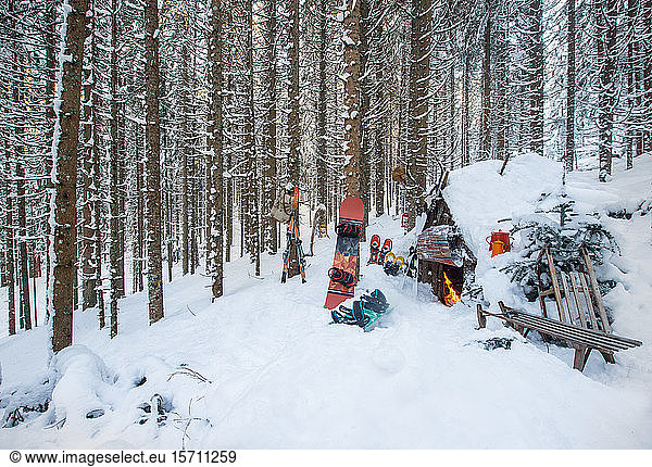 Austria  Salzburg  Altenmarkt im Pongau  Winter sports equipment lying in front of snow-covered forest hut