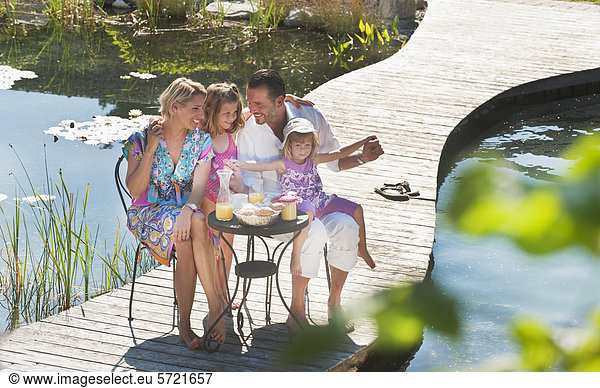Austria  Salzburg County  Family having breakfast on bridge over pond