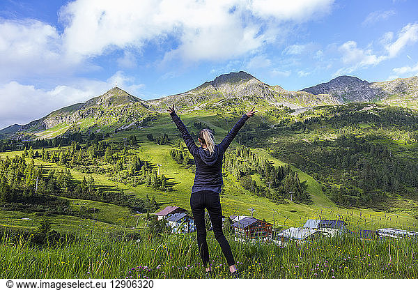 Austria  Salzburg State  Obertauern  woman standing on viewpoint  raised arms  rear view