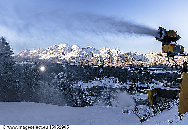 Austria  Styria  Schladming  Snow cannon spraying snow over Planai ski slope at dusk