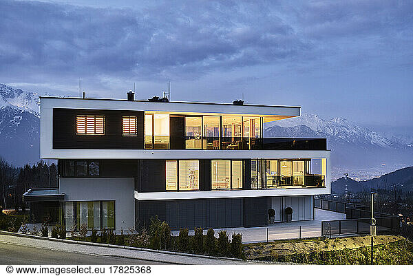 Austria  Tyrol  Illuminated facade of luxurious three-storey house in mountains at dusk