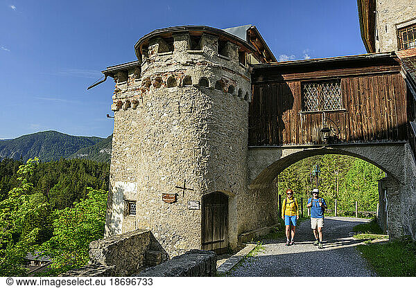 Austria  Tyrol  Nassereith  Hiking pair passing gate of Burg Fernstein