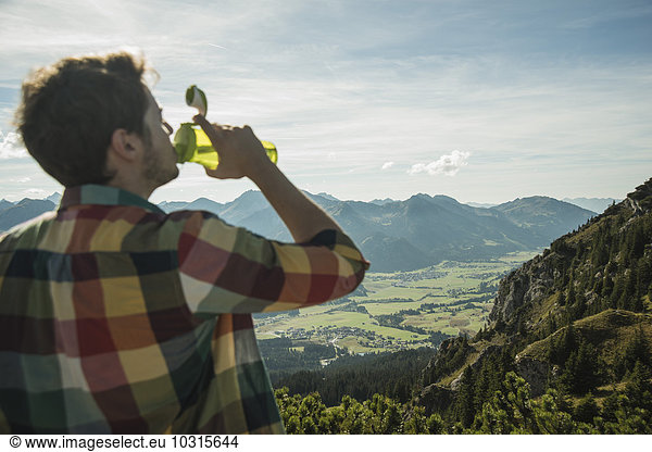 Austria  Tyrol  Tannheimer Tal  young man drinking water in mountainscape