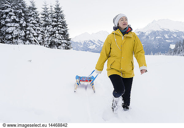 Austria Tyrol Thurn mature woman pulling sledge in snow-covered landscape
