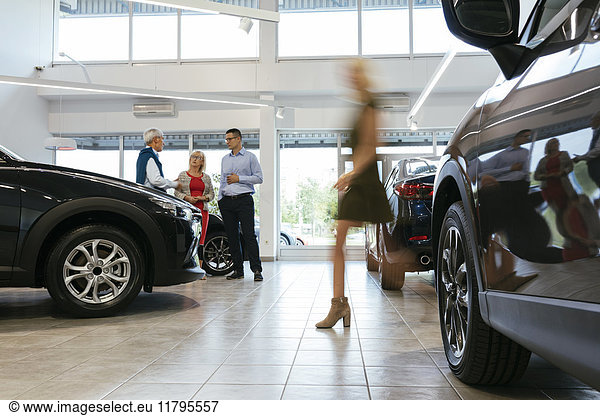 Autohaus berät Kunden mit Frau im Vordergrund