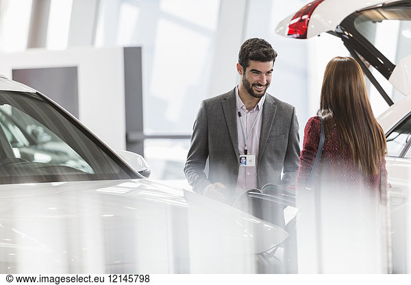 Autoverkäufer hilft Kundin im Autohaus-Showroom