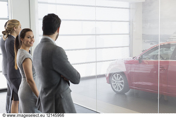 Autoverkäufer suchen neues  rotes Auto im Autohaus-Showroom