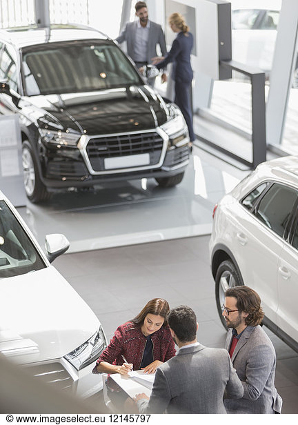 Autoverkäufer und Kunden im Autohaus Showroom
