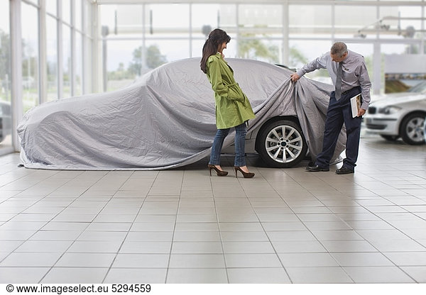 Autoverkäufer zeigt Auto für Frau