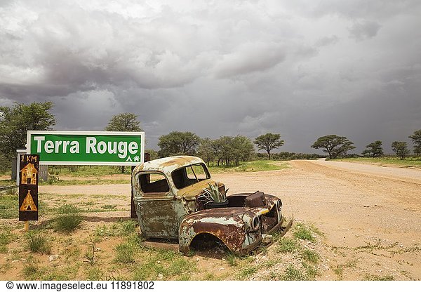 Autowrack am Eingangstor der Gästefarm Terra Rouge Regenzeit mit grüner Vegetation Schotterstraße C 15 Kalahari-Wüste Hardap-Region Namibia Afrika