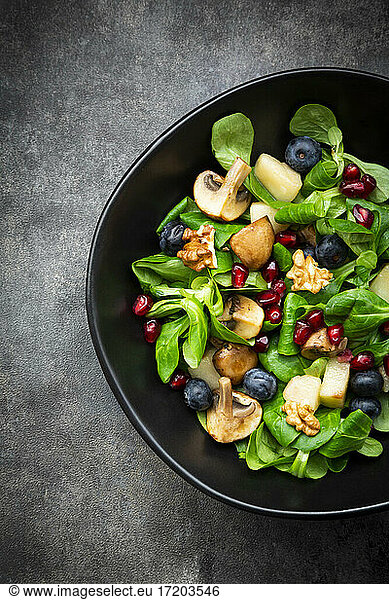 Autumn salad consisting of lamb's lettuce  mushrooms  fried pears  blueberries  pomegranate seeds and walnuts