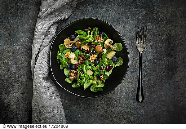 Autumn salad consisting of lamb's lettuce  mushrooms  fried pears  blueberries  pomegranate seeds and walnuts