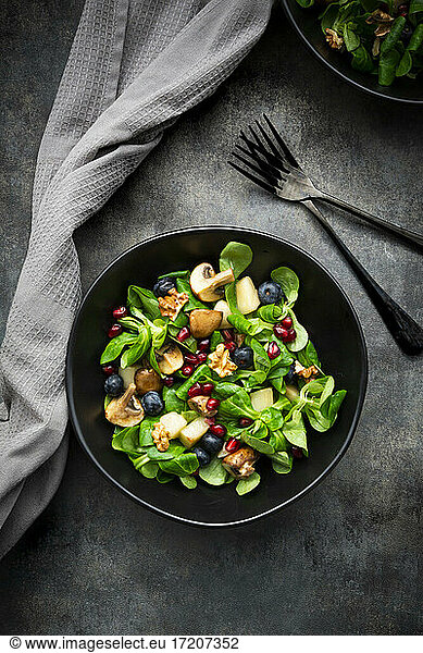 Autumn salad consisting of lambs lettuce  mushrooms  fried pears  blueberries  pomegranate seeds and walnuts