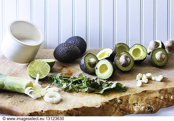 Avocados and cilantro by leeks on cutting board