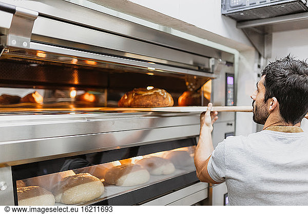 Bäcker backt Brot im Ofen in einer Bäckerei