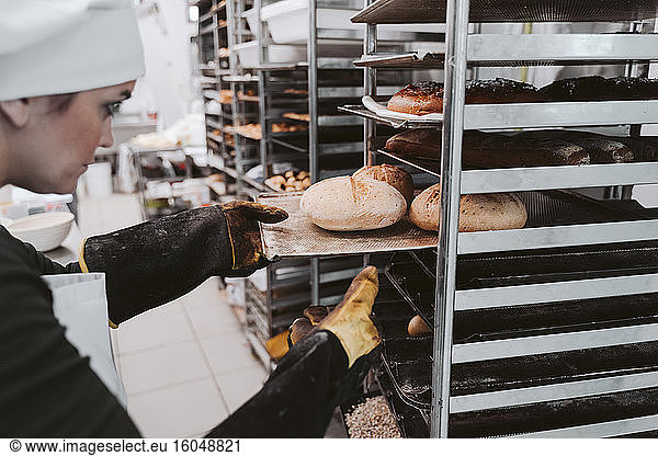 Bäckerin legt Brötchenschale in den Wagen einer Bäckerei ein