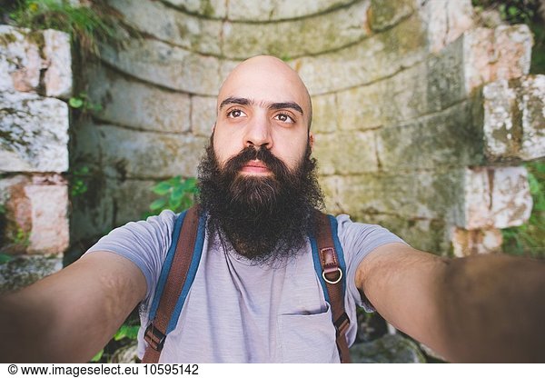Bärtiger Mann  der gegen die alte Backsteinmauer posiert  Garda  Italien