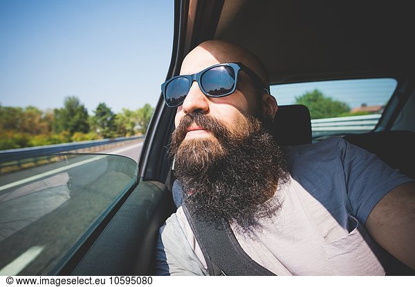 Bärtiger Mann mit Blick aus dem Autofenster auf der Autobahn  Garda  Italien