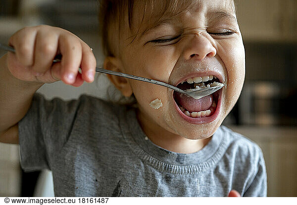 Baby boy eating porridge with spoon