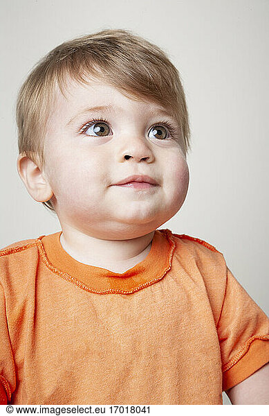 Baby boy in orange t-shirt looking up