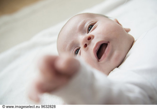 Baby boy lying on bed with mouth open
