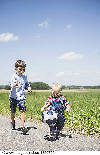 Baby boy playing football with his brother on meadow in the countryside  Bavaria  Germany